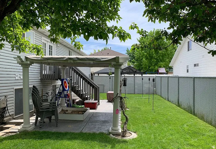 Expansive backyard featuring a manicured lawn, a chain-link fence, and mature trees