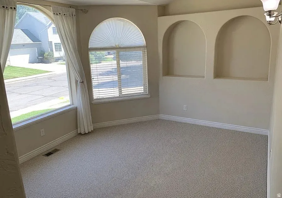 Arch-top windows, arched wall niches, neutral-toned carpeting, and a wall-mounted light fixture
