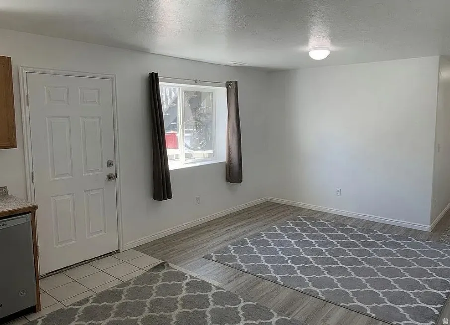 Basement entrance. Recessed window with natural light, wood-finish flooring, overhead dome lighting, white interior door, and tile flooring
