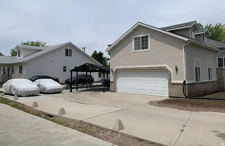 Stucco and stone exterior with arched window accents, attached garage, and paved driveway