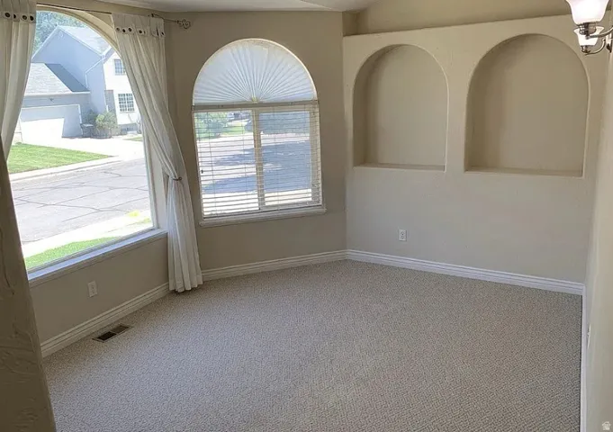 Arch-top windows, arched wall niches, neutral-toned carpeting, and a wall-mounted light fixture