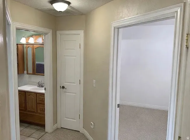 Bathroom vanity with wood cabinetry, integrated sink, and wall-mounted light fixture