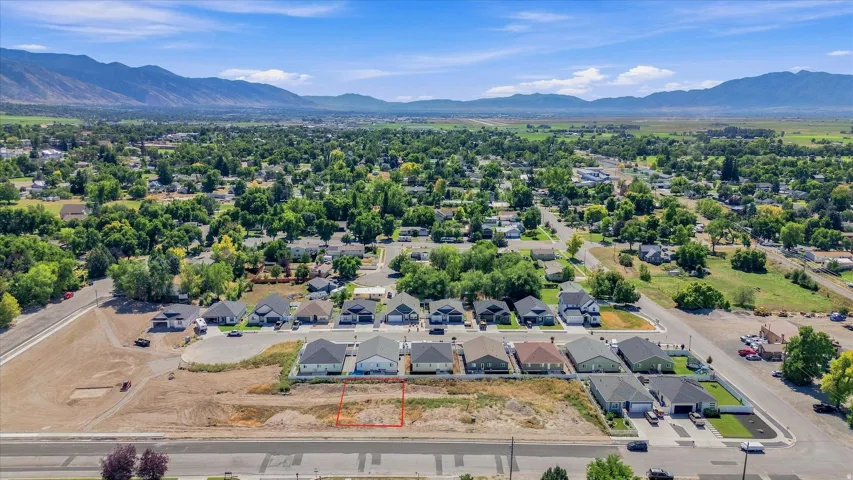 Expansive lot within a developed neighborhood, featuring surrounding established homes and distant mountain ranges