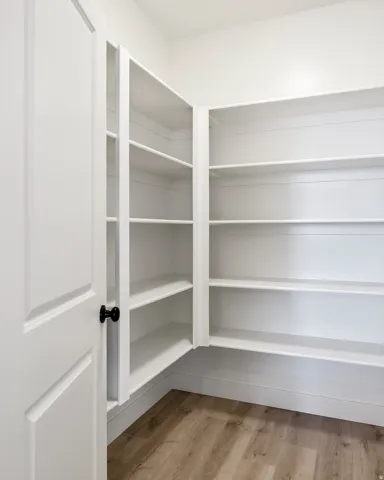 Built-in shelving with multiple levels, white finishes, and wood-finish flooring