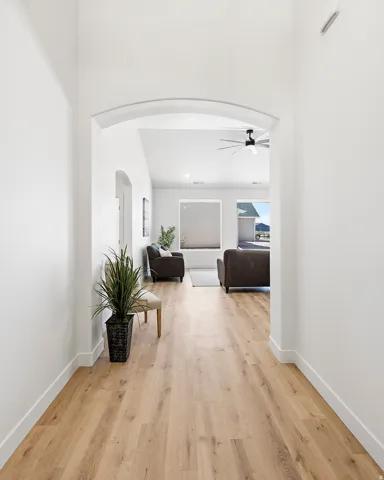 Arched entryway leading to an open-concept living space with vaulted ceilings, wood-finish flooring, and large windows