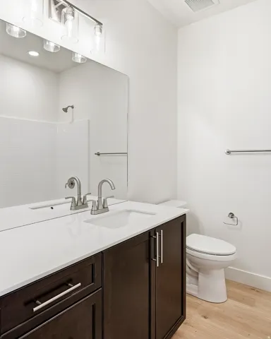 Double vanity with a white countertop and dark wood-finish cabinetry, featuring dual undermount sinks and brushed nickel faucets
