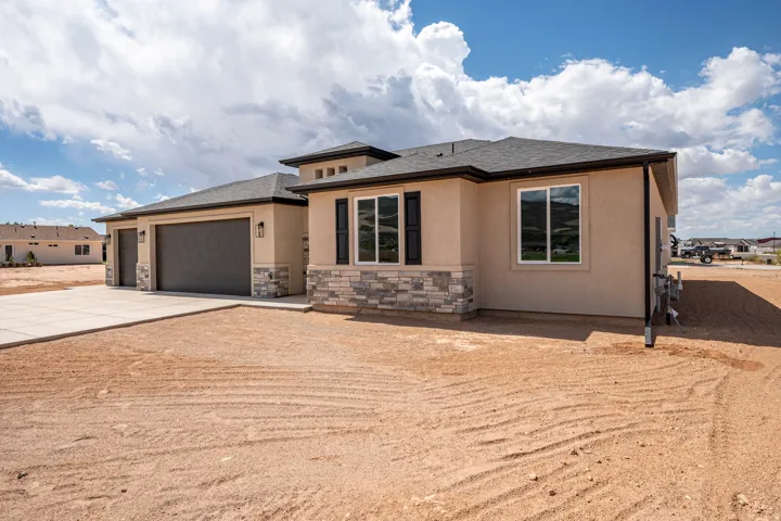 Stucco exterior with stone veneer accents, dark shingle roof, attached garage with textured door, and modern exterior light fixtures
