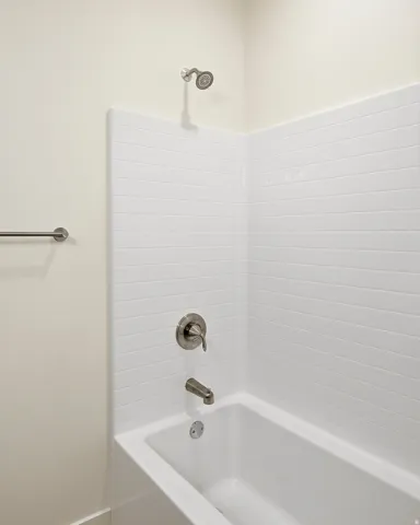 Bathtub with white subway tile surround, brushed nickel fixtures, and a coordinating towel bar
