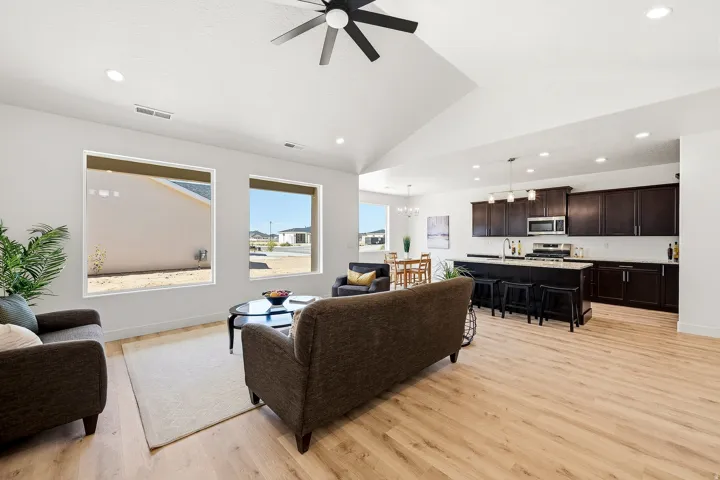 Vaulted ceilings, recessed lighting, wood-finish flooring, dark wood cabinetry, and a kitchen island with pendant lighting