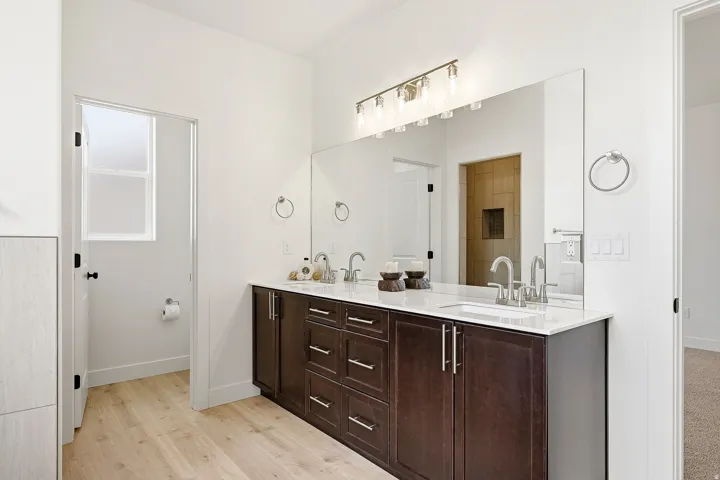 Double vanity with under-mount sinks, wood-finish cabinetry, and a full-width mirror