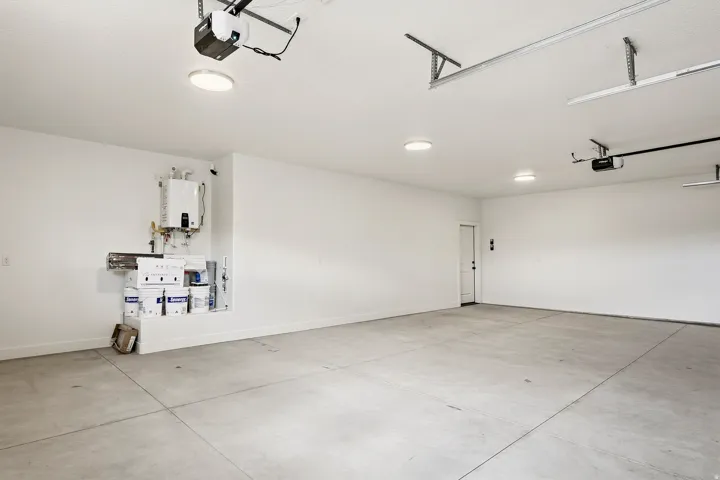 Expansive garage featuring a concrete floor, multiple ceiling-mounted light fixtures, and a tankless water heater