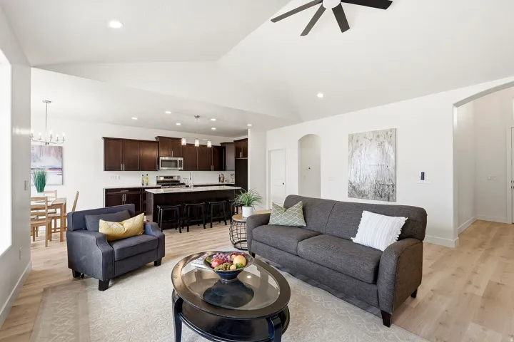 Vaulted ceiling with a ceiling fan, light wood-finish flooring, dark wood cabinetry, recessed lighting, and white countertops