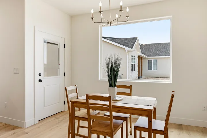 Recessed lighting, wood-finish flooring, white paneled door with glass insert, large window frame, and overhead chandelier