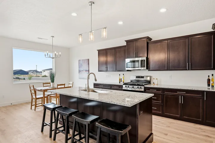 Kitchen featuring dark wood cabinetry, stainless steel appliances, light-toned countertops, and wood-finish flooring