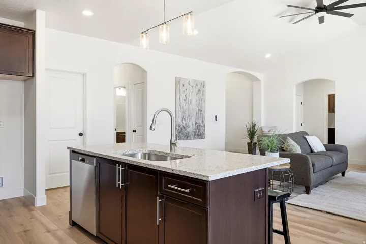 Kitchen island with light-toned countertop, stainless steel sink, and integrated dishwasher