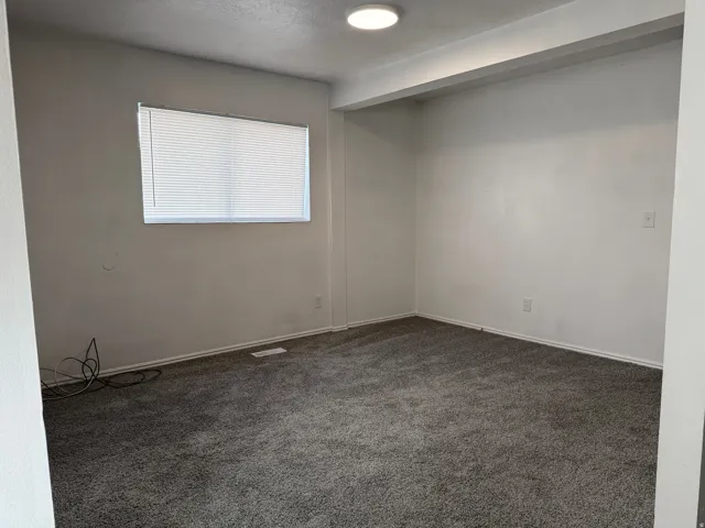 Carpeted room featuring a window with horizontal blinds, overhead flush mount lighting, and neutral wall tones