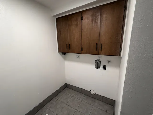 Upper cabinetry with dark hardware, tile flooring, and light-toned walls