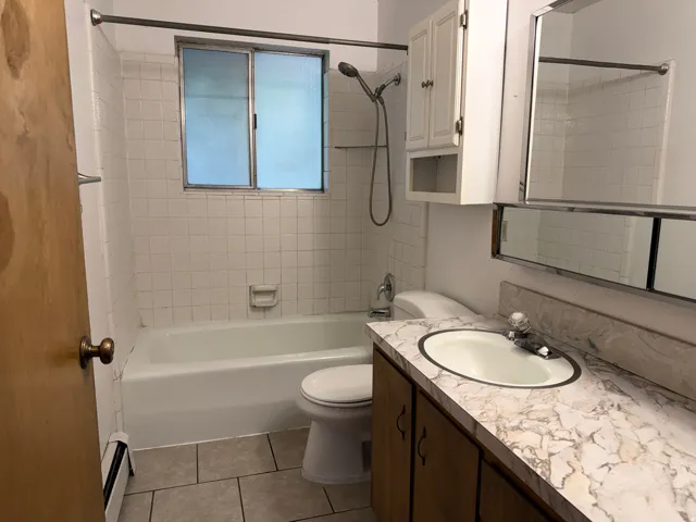 Bathroom featuring a white bathtub, ceramic tile walls, a vanity with an integrated sink, and a mirrored medicine cabinet