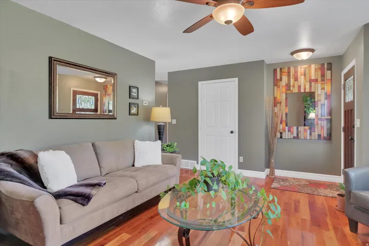 Wood-finish flooring, ceiling fan with integrated lighting, paneled interior door, and a partially visible exterior door with decorative glass inserts