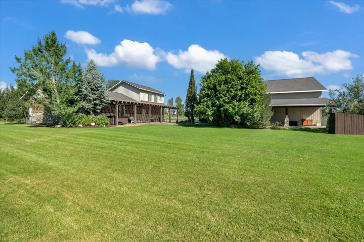 Expansive lawn area with a two-story residence featuring a covered patio with a pergola