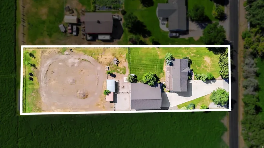 Expansive property featuring a main residence, secondary structure, a circular arena, extensive green space, and a paved driveway