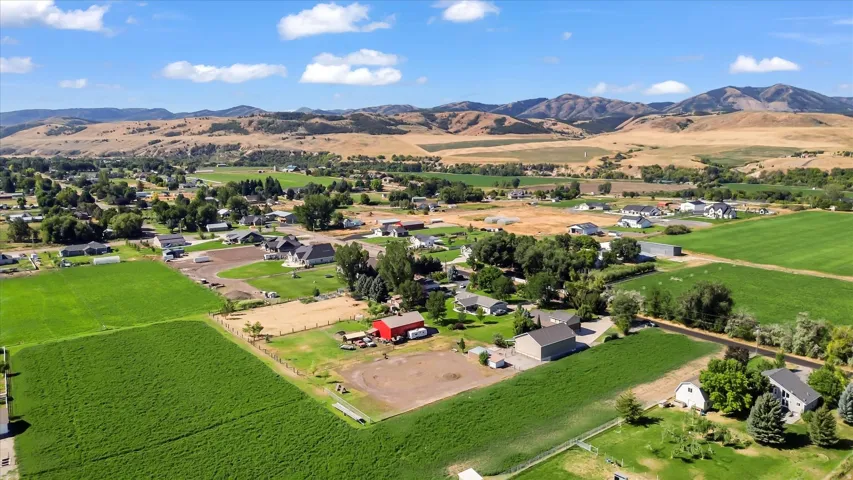 Expansive green fields, mature trees, and residential properties with mountainous terrain
