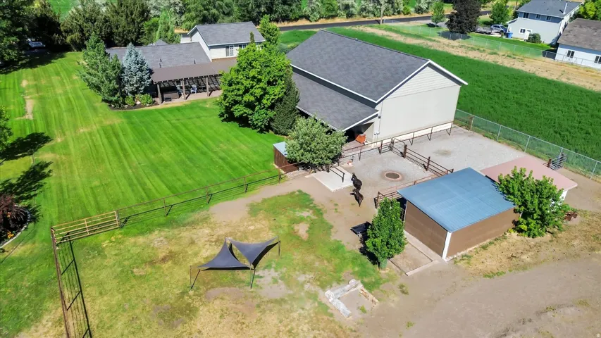 Expansive green lawn, fenced animal enclosure, detached shelter structure, mature trees, and covered patio area