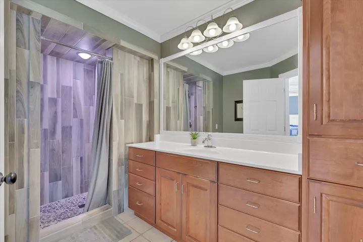 Bathroom featuring a wood-finish vanity with white countertop, large wall-mounted mirror, and overhead lighting