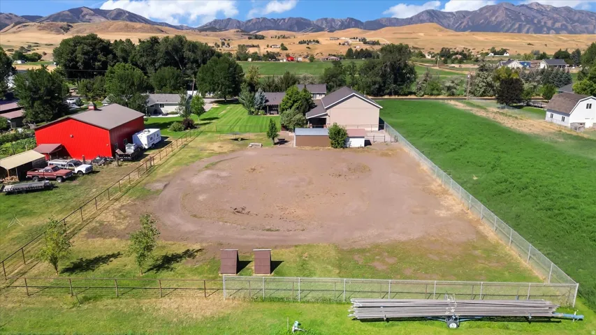 Expansive lot featuring a fenced perimeter, a large red barn, a secondary dwelling, a substantial graded area, and surrounding open green space