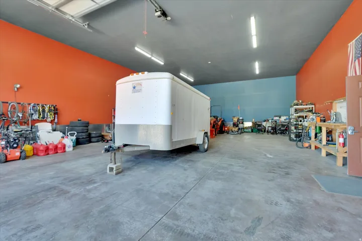 Spacious workshop with concrete flooring, high ceilings, and fluorescent lighting