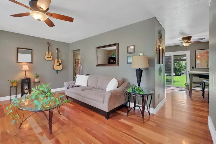 Wood-finish flooring throughout, ceiling fan with integrated lighting, neutral wall tones, and glass sliding doors leading to the exterior
