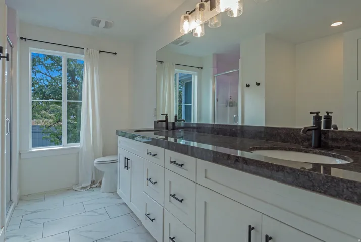 Dual vanity with undermount sinks, stone countertop, and matte black fixtures