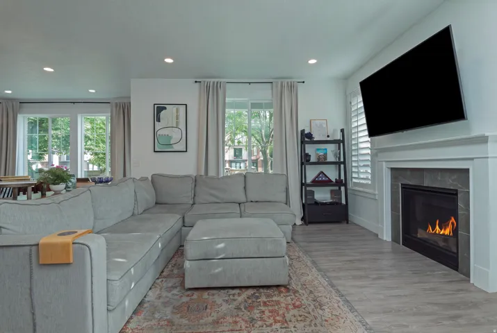 Recessed lighting, wood-finish flooring, multiple windows with plantation shutters, built-in fireplace with a stone surround, and an open layout
