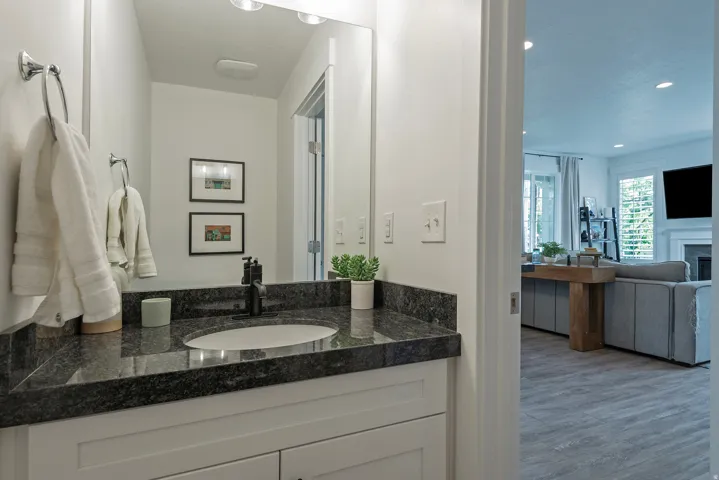 Bathroom vanity with dark granite countertop, undermount sink, and matte black faucet