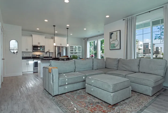 Open-concept living area with wood-finish flooring, recessed lighting, and large windows