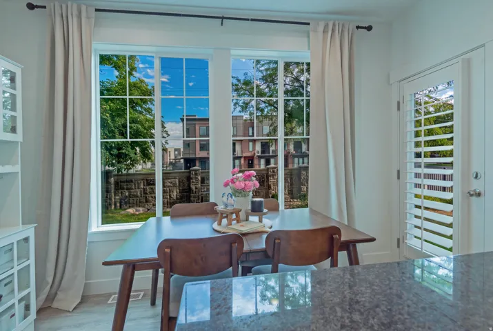 Dual pane windows with grid patterns, a glass-paneled door with interior plantation shutters, light wood-finish flooring, and a built-in display cabinet