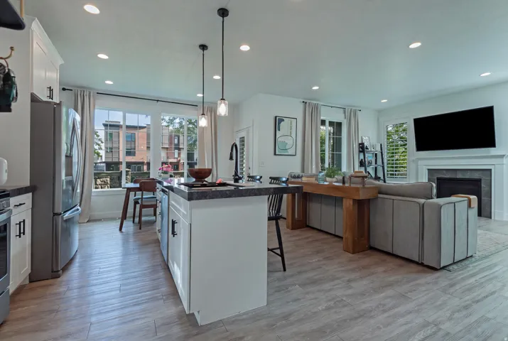 Open-concept living space featuring wood-finish flooring, recessed lighting, and a fireplace with a mantel