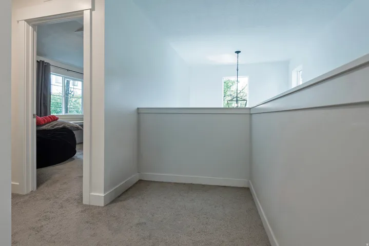 Carpeted hallway with white painted walls and white trim