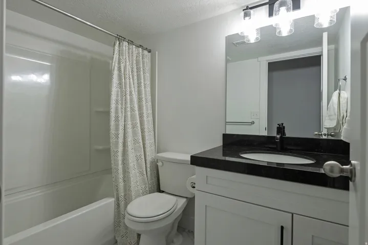 White vanity with a dark stone countertop, undermount sink, and matte black faucet