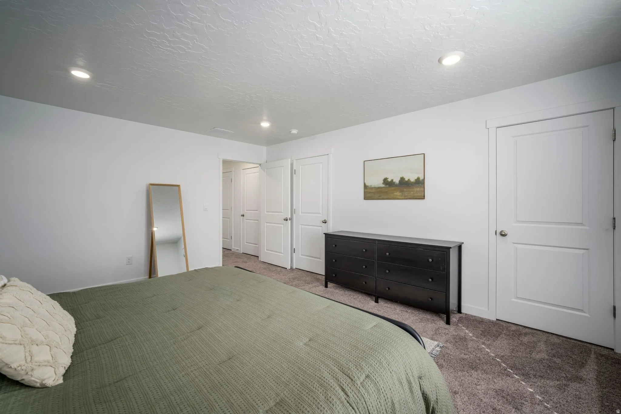 Master bedroom with recessed lighting, white walls, textured carpeting, and multiple paneled doors