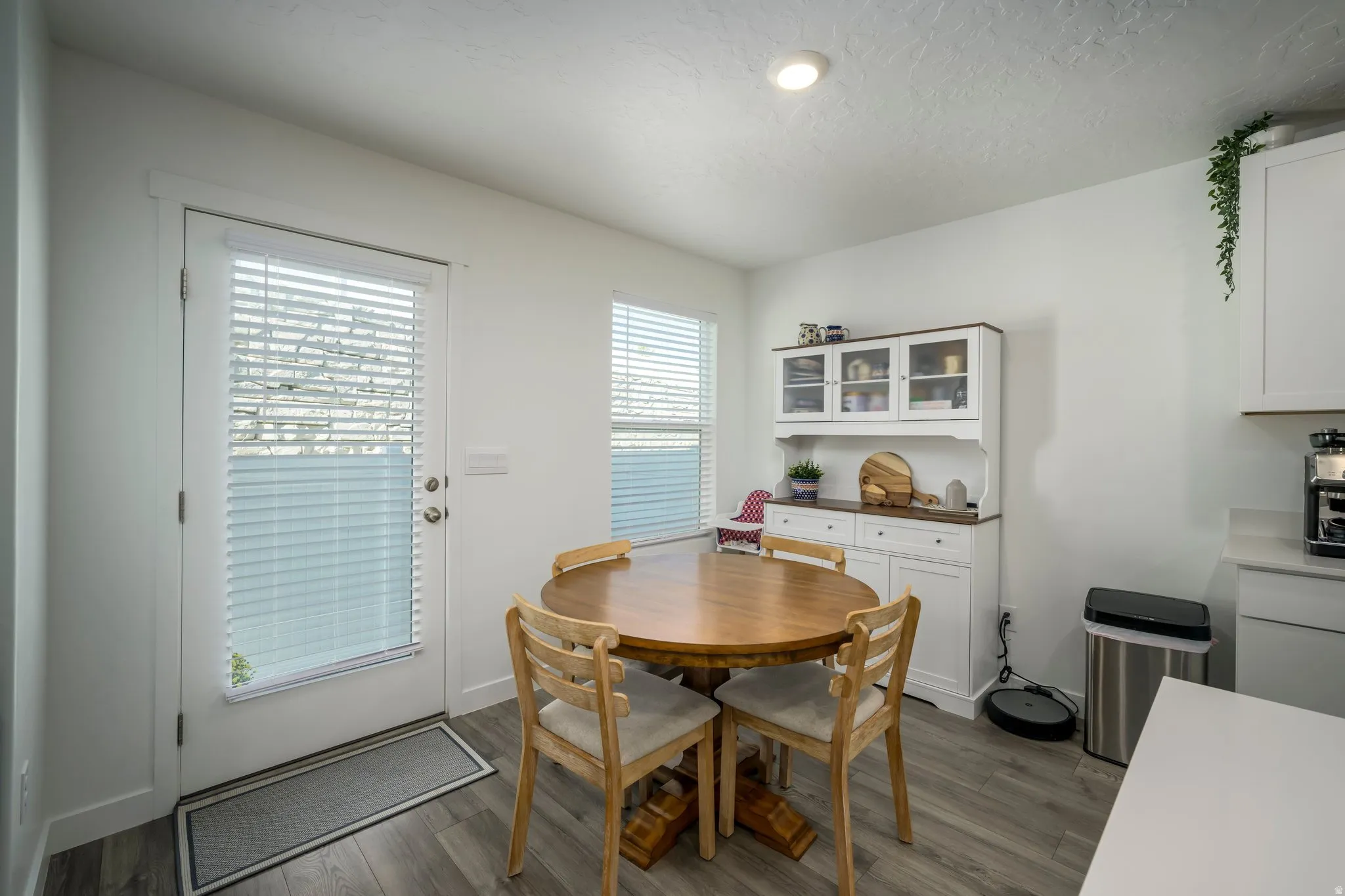 Wood-finish flooring, recessed lighting, built-in display hutch with glass-front cabinets, white base cabinets with dark wood-finish countertop