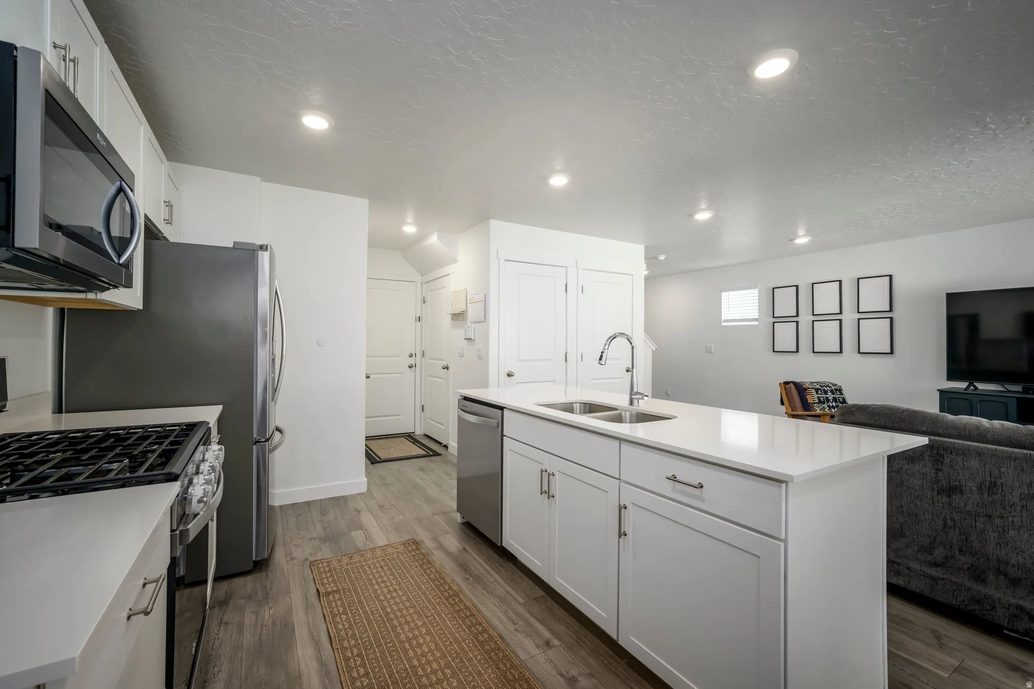 Contemporary kitchen featuring a center island, white cabinetry, integrated stainless steel appliances, and wood-finish flooring