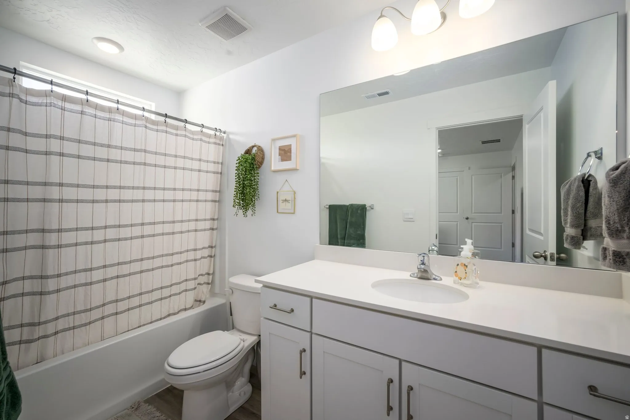 White vanity with a single basin, stainless steel faucet, and expansive wall-mounted mirror