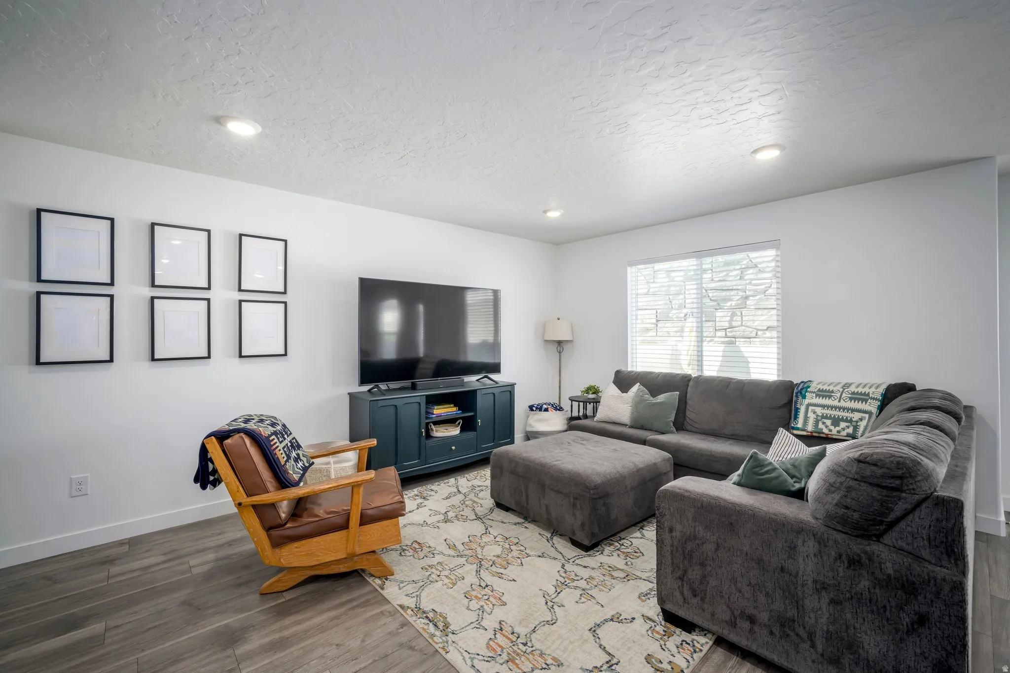 Recessed ceiling lighting, wood-finish flooring, and a large window with blinds