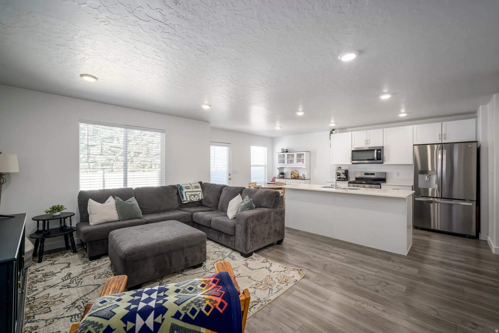 Open-concept living space featuring wood-finish flooring, recessed lighting, and a kitchen island with seating