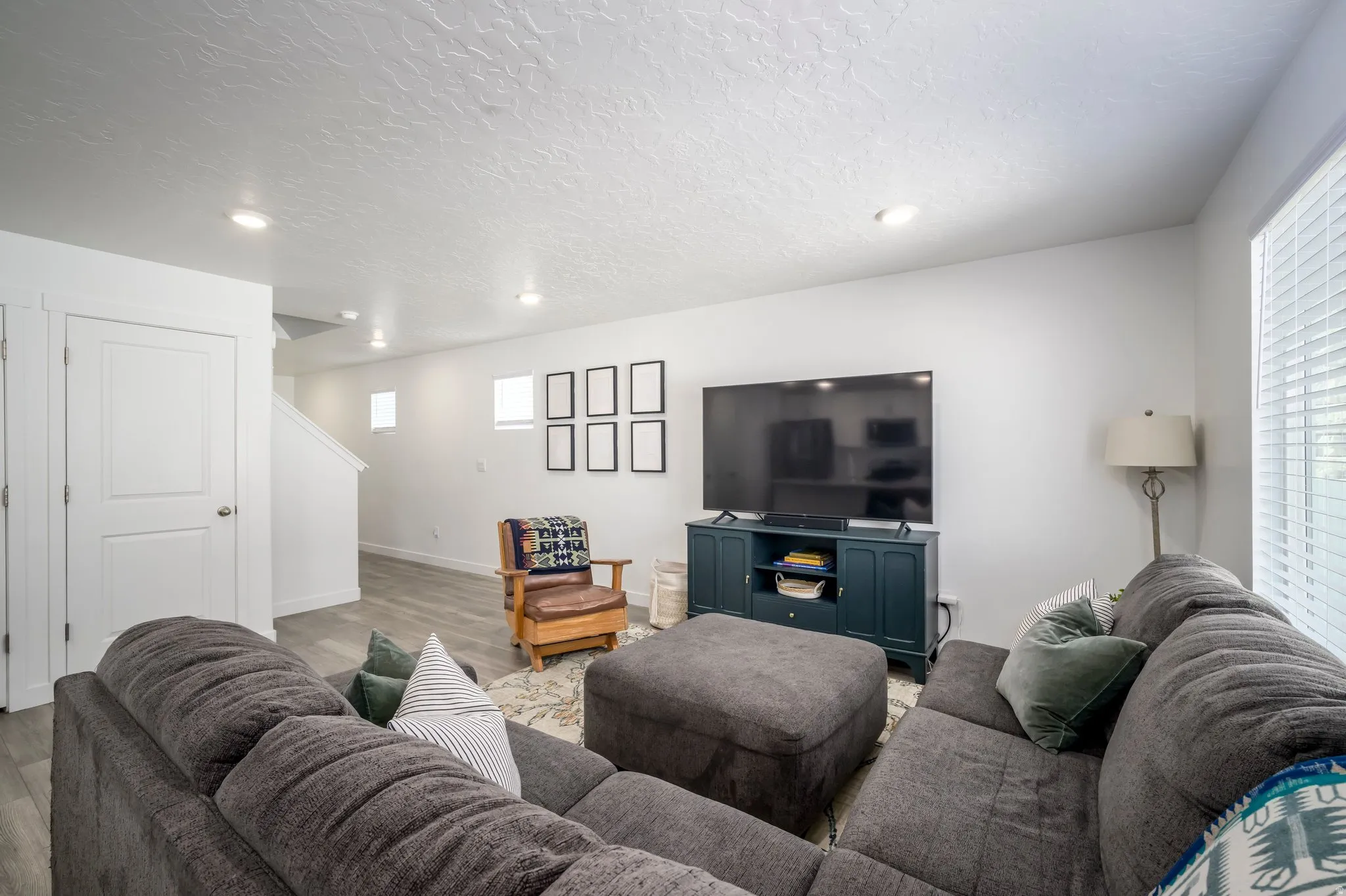 Recessed lighting, wood-finish flooring, white walls, and a built-in media console