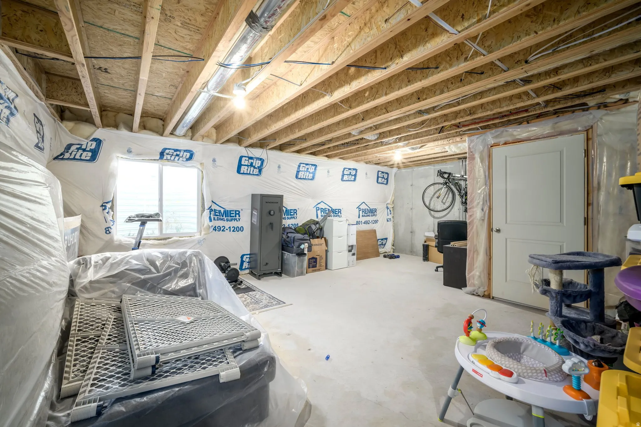 Unfinished basement with exposed ceiling joists, concrete floor, and a single window