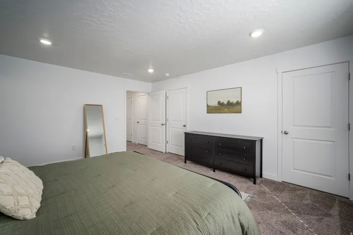 Master bedroom with recessed lighting, white walls, textured carpeting, and multiple paneled doors