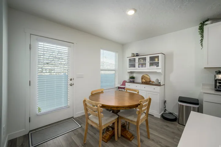 Wood-finish flooring, recessed lighting, built-in display hutch with glass-front cabinets, white base cabinets with dark wood-finish countertop