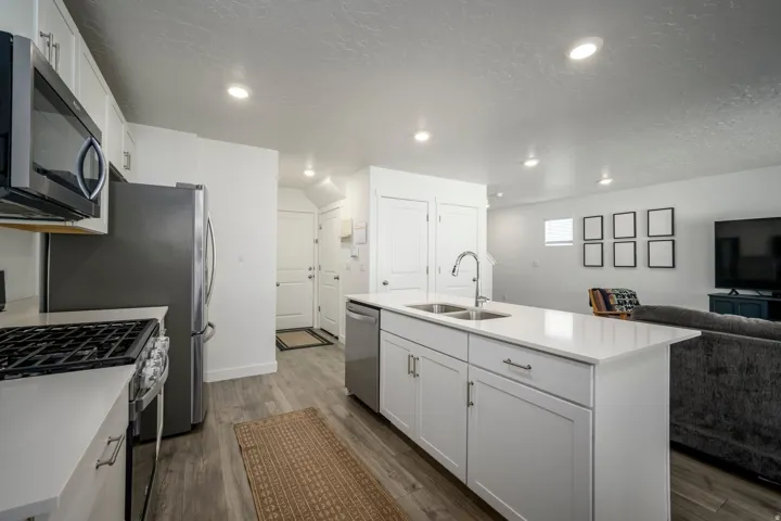 Contemporary kitchen featuring a center island, white cabinetry, integrated stainless steel appliances, and wood-finish flooring
